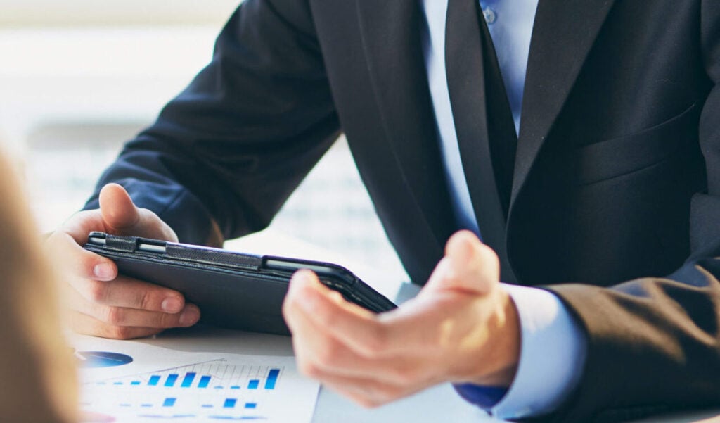 Persona in riunione di lavoro con tablet e documenti di analisi, durante attività di leadership e gestione del cambiamento.